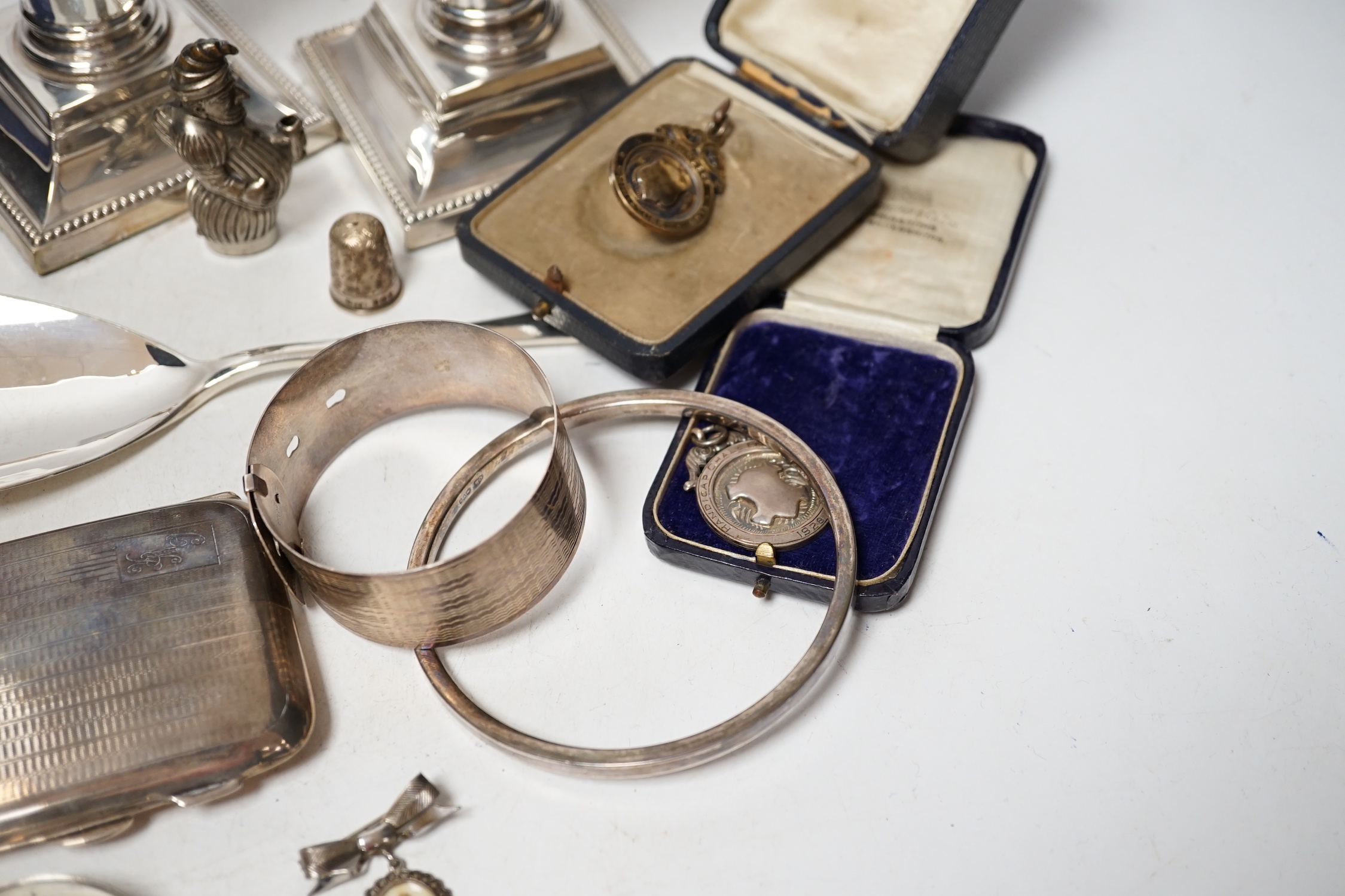 Sundry small silver including a cased preserve spoon, by Albert Edward Jones, a pair of mounted dwarf candlesticks, serving spoon, thimbles, napkin ring etc.